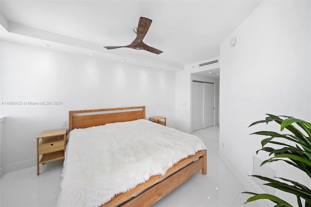 bedroom with ceiling fan, light tile patterned flooring, and a closet