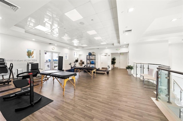 gym with a raised ceiling, a drop ceiling, and hardwood / wood-style flooring