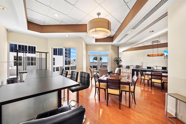 dining room with a tray ceiling and light wood-type flooring