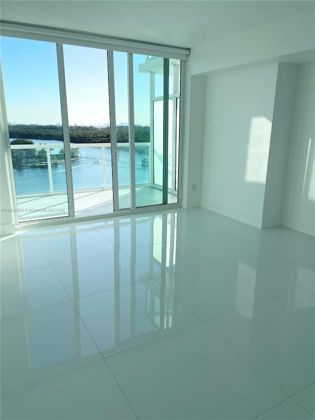 unfurnished room with a water view, floor to ceiling windows, and tile patterned flooring