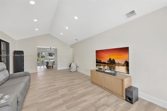 living room featuring a chandelier, light hardwood / wood-style flooring, and vaulted ceiling