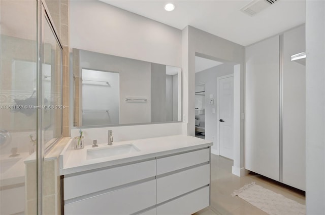 bathroom with an enclosed shower, vanity, and tile patterned flooring