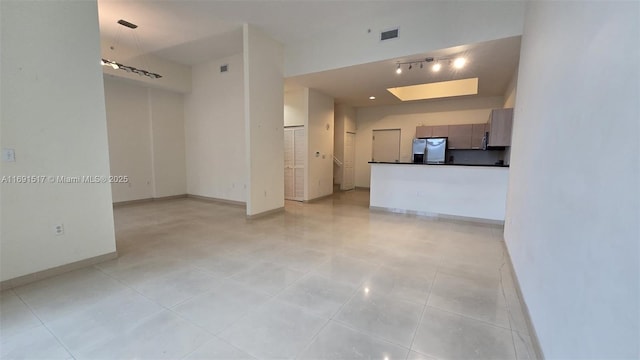 unfurnished living room featuring light tile patterned floors and a skylight