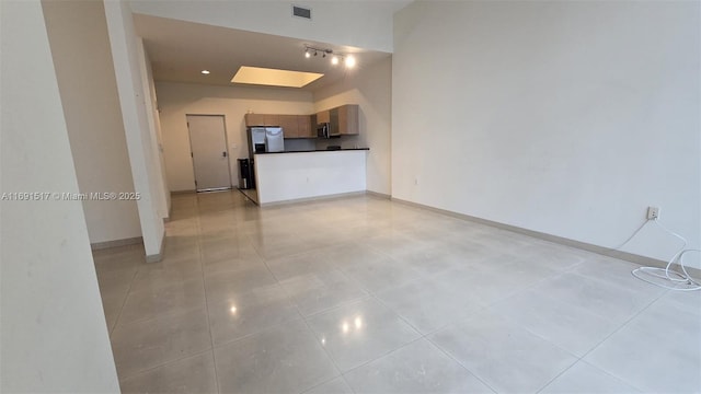 unfurnished living room featuring light tile patterned floors and a skylight