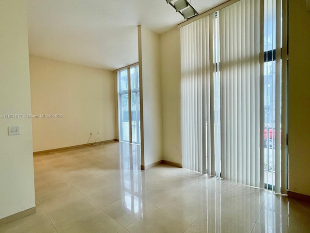 tiled empty room featuring a wall of windows