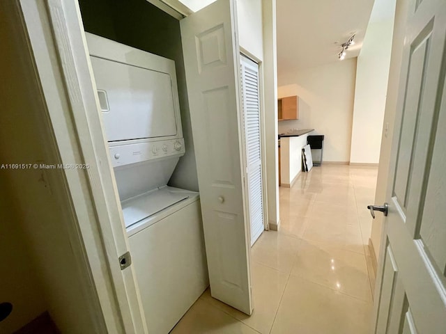 washroom with stacked washer / dryer and light tile patterned floors