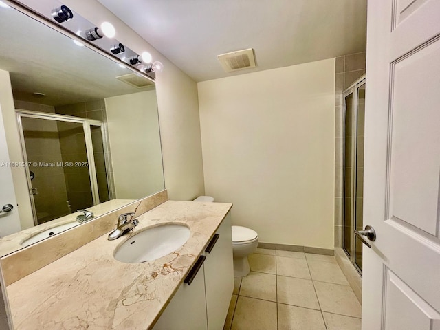 bathroom featuring vanity, a shower with door, tile patterned floors, and toilet