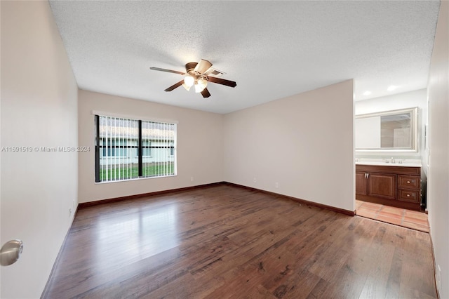 empty room with wood-type flooring, a textured ceiling, ceiling fan, and sink