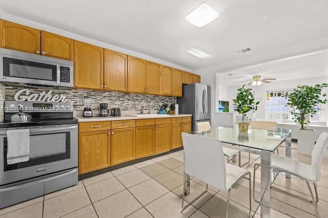 kitchen with light tile patterned flooring, appliances with stainless steel finishes, sink, decorative backsplash, and ceiling fan