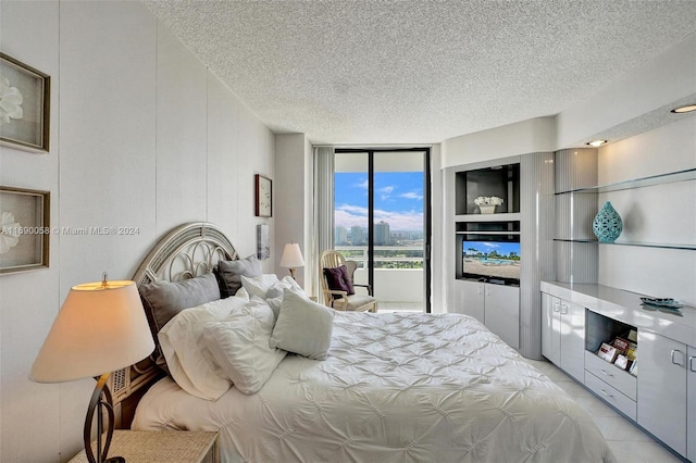 bedroom with expansive windows, access to exterior, and a textured ceiling