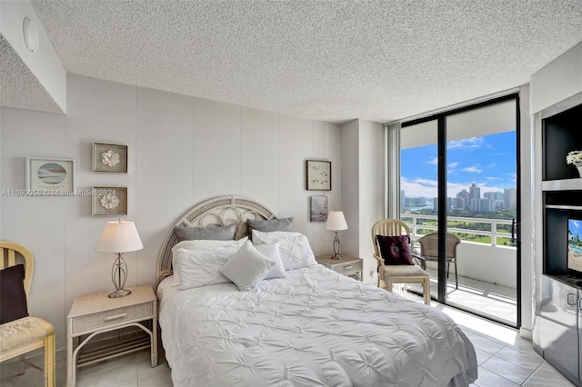 tiled bedroom featuring access to exterior, a textured ceiling, and floor to ceiling windows