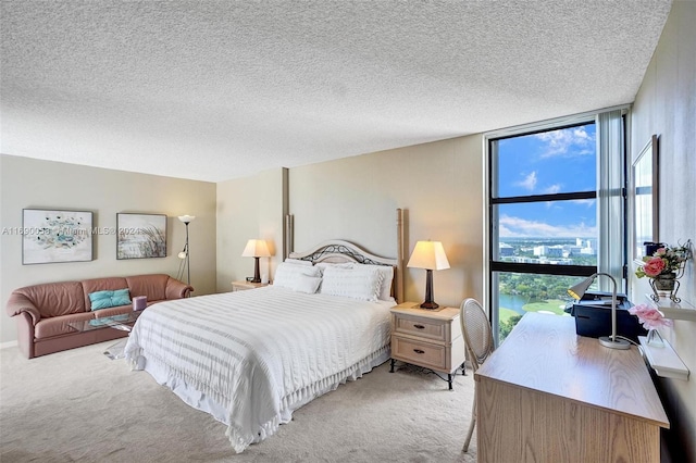 bedroom featuring light carpet, a textured ceiling, and floor to ceiling windows