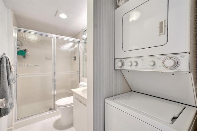 bathroom featuring stacked washer and dryer, vanity, toilet, and walk in shower