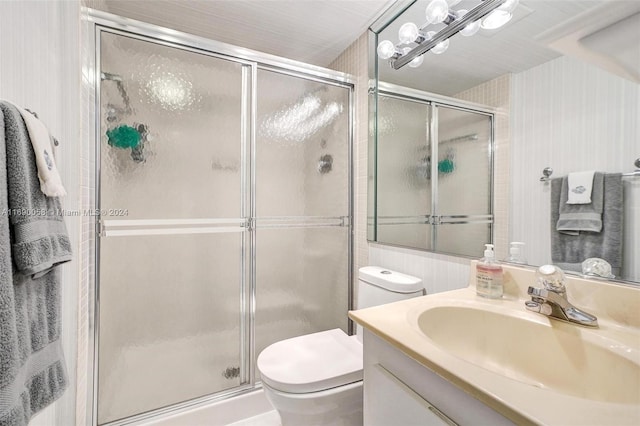 bathroom with vanity, toilet, and a shower with door