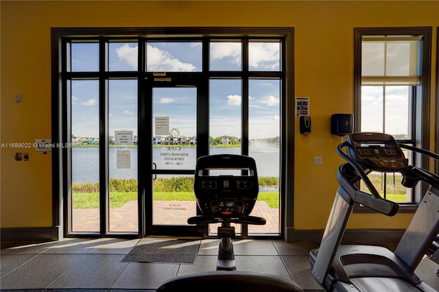 gym featuring a water view and a healthy amount of sunlight