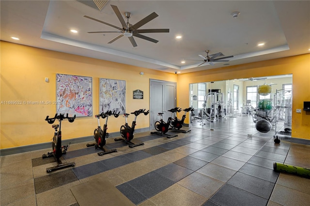 exercise room with a raised ceiling and ceiling fan