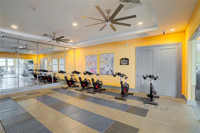 exercise room with a tray ceiling and ceiling fan