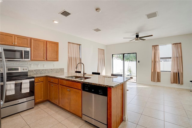 kitchen with kitchen peninsula, appliances with stainless steel finishes, light tile patterned floors, and sink