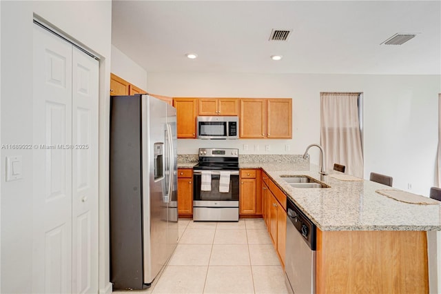 kitchen with kitchen peninsula, light stone countertops, stainless steel appliances, sink, and light tile patterned flooring