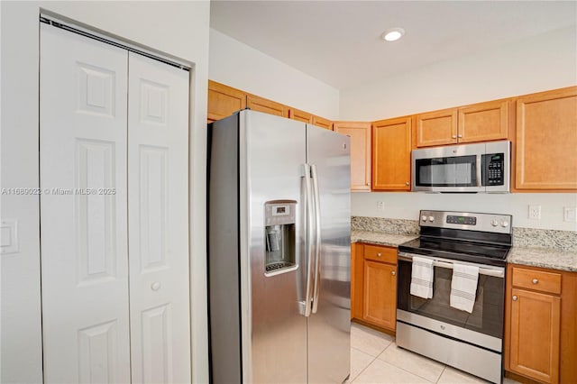 kitchen with appliances with stainless steel finishes, light tile patterned floors, and light stone counters