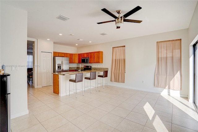 kitchen featuring ceiling fan, stainless steel appliances, a kitchen breakfast bar, kitchen peninsula, and light tile patterned flooring