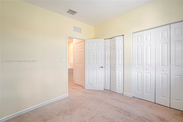 unfurnished bedroom with multiple closets and light carpet