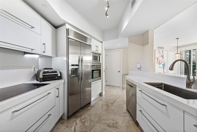 kitchen with white cabinetry, stainless steel appliances, sink, and decorative light fixtures