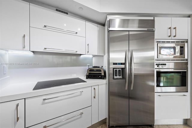 kitchen with white cabinets, built in fridge, and black electric cooktop