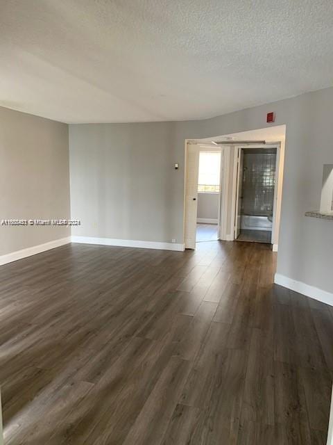 unfurnished room featuring dark wood-type flooring and a textured ceiling