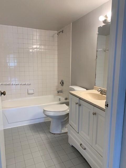 full bathroom with toilet, tiled shower / bath combo, vanity, and tile patterned floors