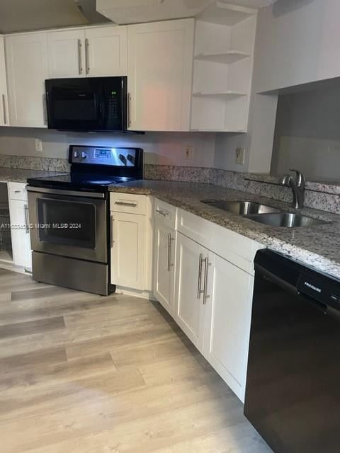 kitchen featuring black appliances, light wood-type flooring, stone countertops, sink, and white cabinets