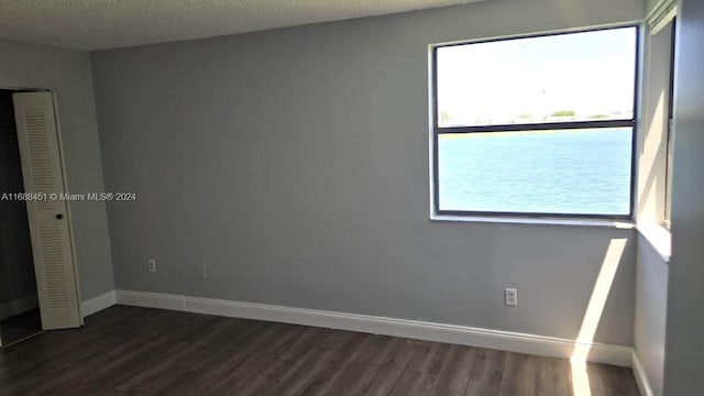 spare room featuring dark wood-type flooring and a textured ceiling