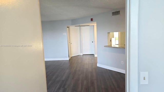 corridor featuring dark wood-type flooring and a textured ceiling