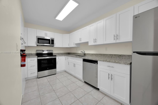 kitchen featuring white cabinets, stainless steel appliances, sink, and light stone countertops