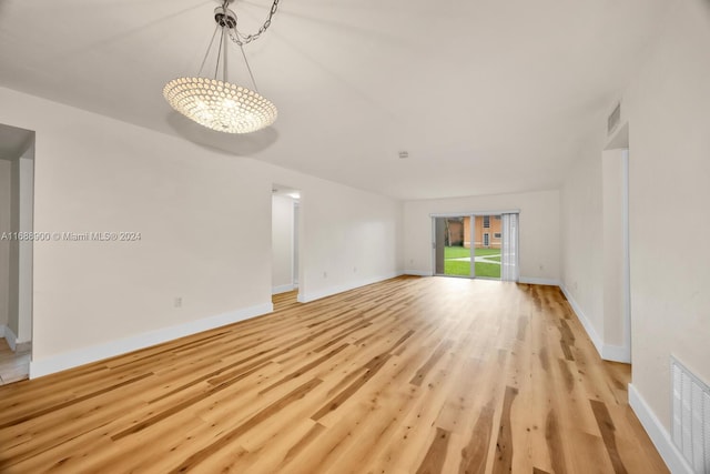 unfurnished living room with a notable chandelier and light hardwood / wood-style flooring