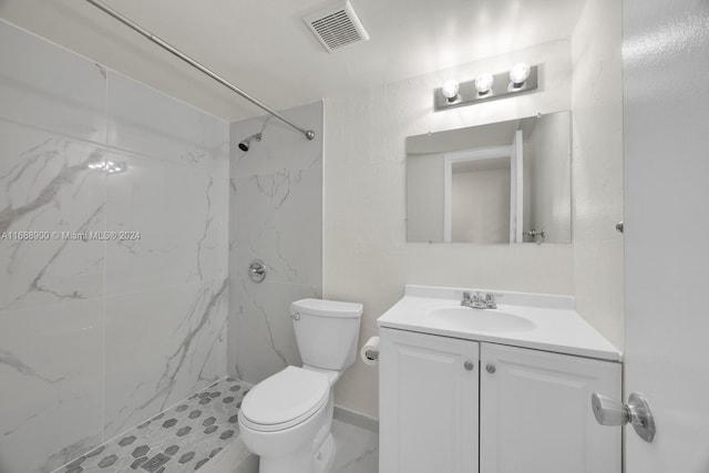 bathroom with tiled shower, toilet, and vanity