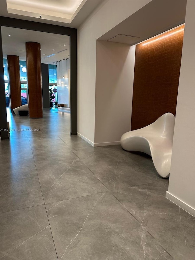 corridor with a tray ceiling and concrete floors