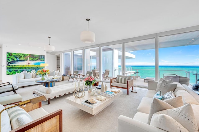 living room with light colored carpet, a water view, and floor to ceiling windows