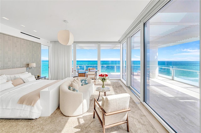 carpeted bedroom featuring expansive windows, a water view, multiple windows, and access to exterior