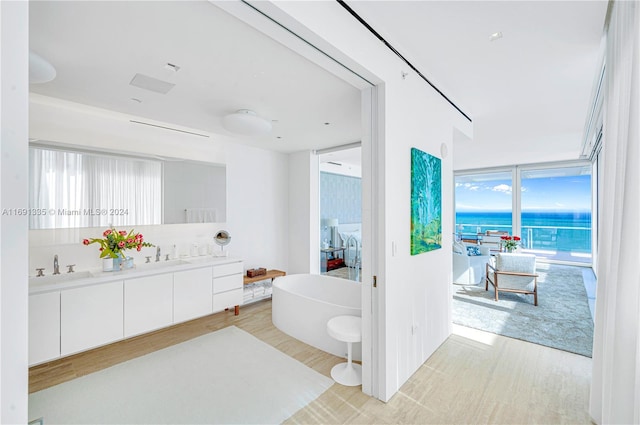 bathroom with vanity, hardwood / wood-style flooring, floor to ceiling windows, and a bath