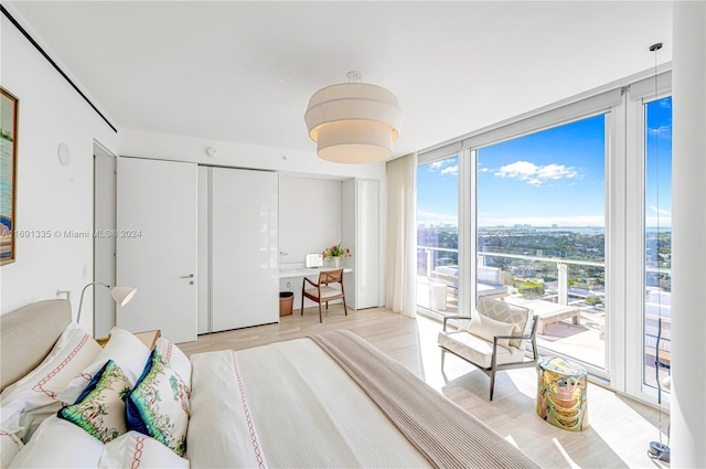 bedroom featuring access to exterior, light wood-type flooring, and expansive windows