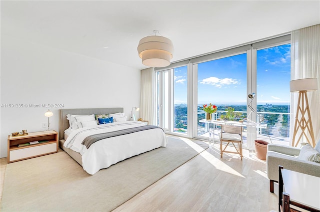 bedroom featuring expansive windows and light hardwood / wood-style flooring