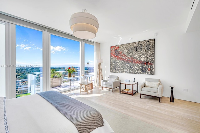 bedroom with hardwood / wood-style flooring, floor to ceiling windows, and access to outside