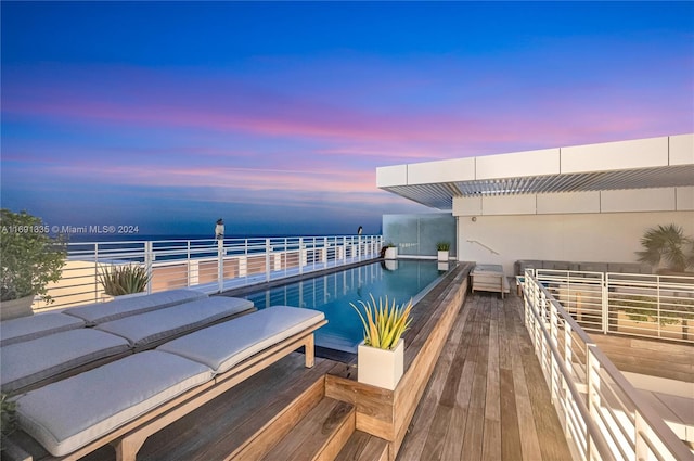 pool at dusk featuring a water view