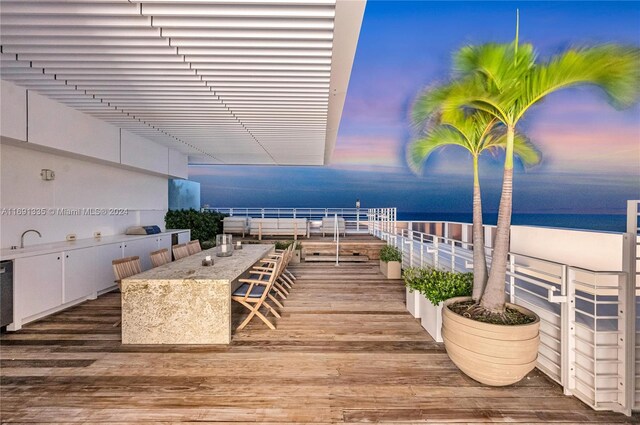 deck at dusk featuring a water view