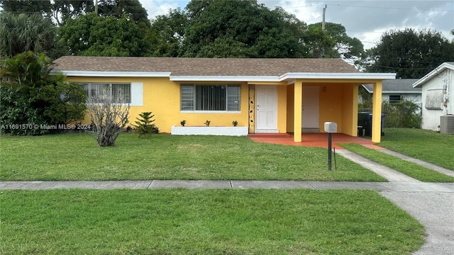 single story home featuring a carport, a front lawn, and central air condition unit