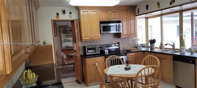 kitchen with tasteful backsplash, light tile patterned flooring, appliances with stainless steel finishes, and sink