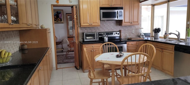 kitchen with sink, light tile patterned floors, stainless steel appliances, and decorative backsplash