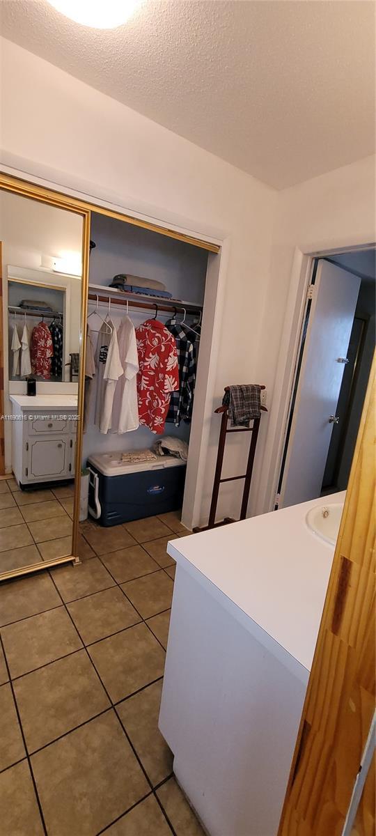 interior space featuring tile patterned flooring, sink, a textured ceiling, and a closet