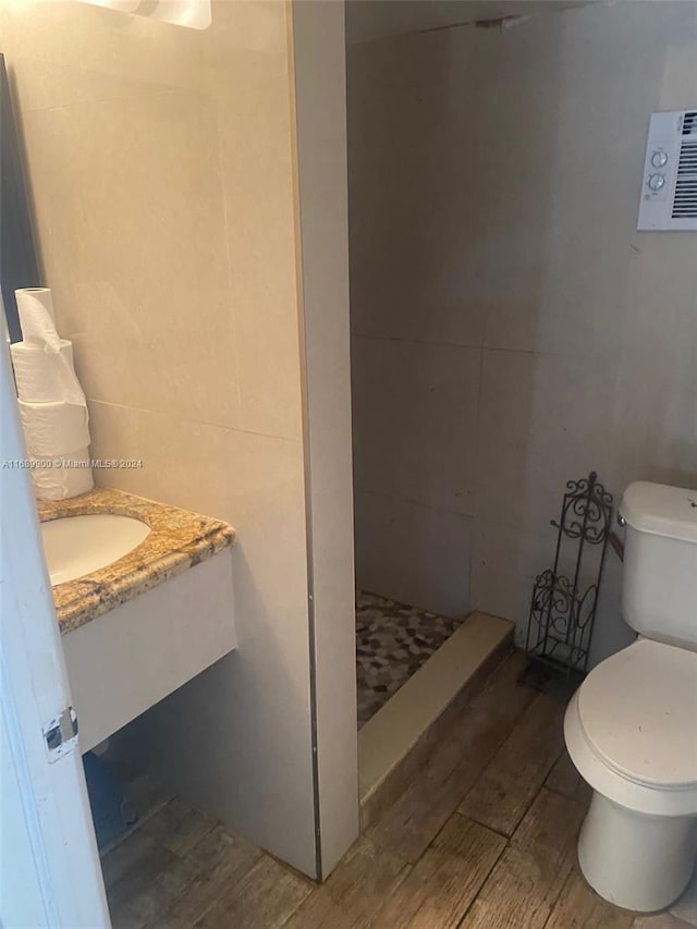 bathroom featuring hardwood / wood-style floors, vanity, toilet, and a shower